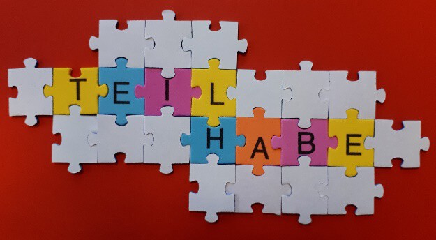 Bild: Puzzleteile auf einem roten Hintergrund, die teilweise zusammengefügt sind und das Wort TEILHABE formen, symbolisieren die Unterstützung und Beratung, die die Ergänzende unabhängige Teilhabeberatung (EUTB) für Menschen mit Behinderungen und ihre Angehörigen anbietet.